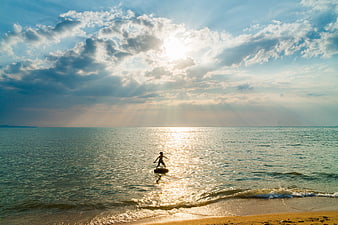 Child Silhouette on Surfboard in Ocean at Sunset