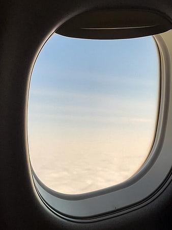 View from airplane window above clouds at sunset