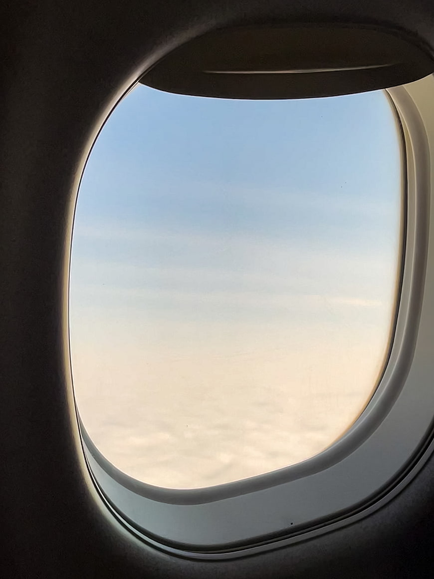 View from airplane window above clouds at sunset