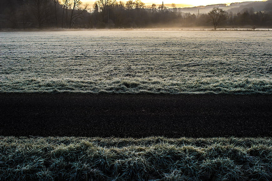 Frosty Winter Field with Dark Path at Sunrise