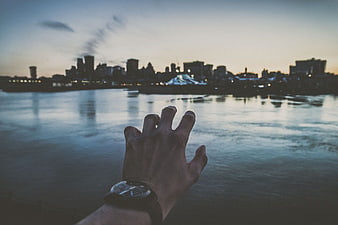 Hand with Watch Reaching Towards City Skyline at Dusk
