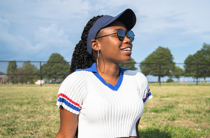 Happy Black Woman in Visor and Sunglasses in Park
