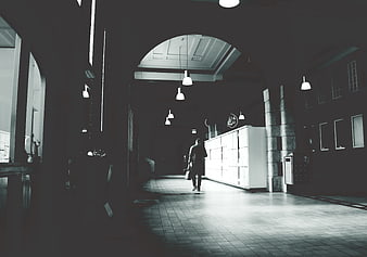Man Walking Away in Dark Architectural Corridor