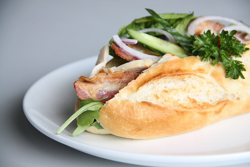 Close-up of a bacon and chicken sandwich on a white plate