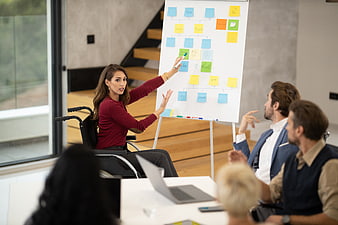 Woman in wheelchair leading business meeting with sticky notes