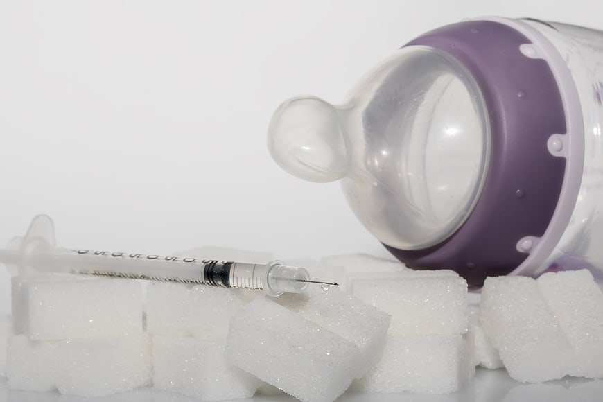 Insulin Syringe and Sugar Cubes Next to Baby Bottle