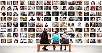 People viewing diverse faces gallery wall in museum