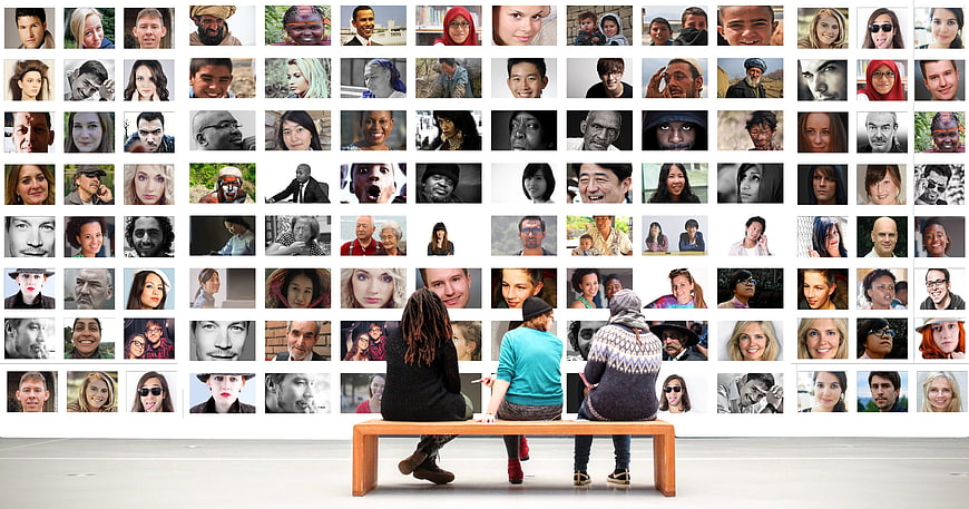 People viewing diverse faces gallery wall in museum