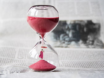 Miniature monk with umbrella inside hourglass on newspaper