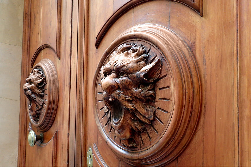 Close-up of ornate carved wooden lion head door knocker