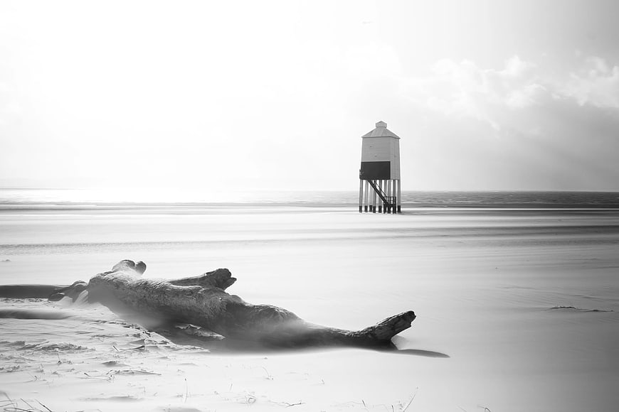 Black and white lifeguard tower on misty beach with driftwood