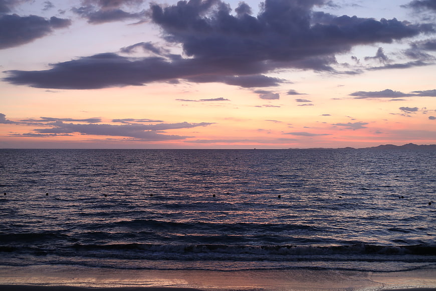 Serene ocean sunset with purple clouds and calm waves