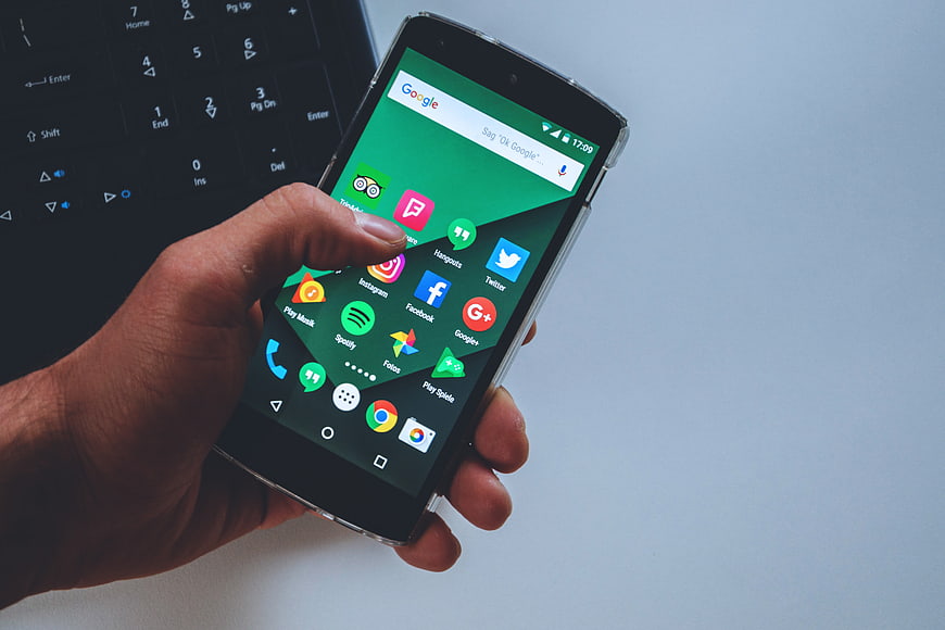 Hand holding smartphone with social media apps on screen