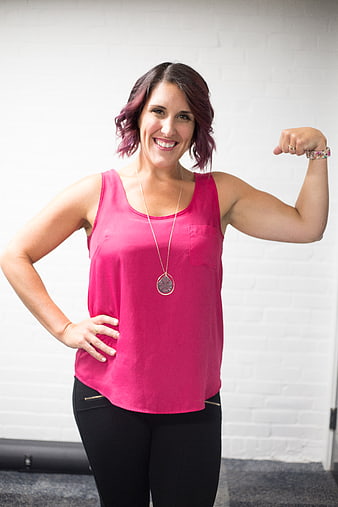 Confident woman flexing bicep in pink top