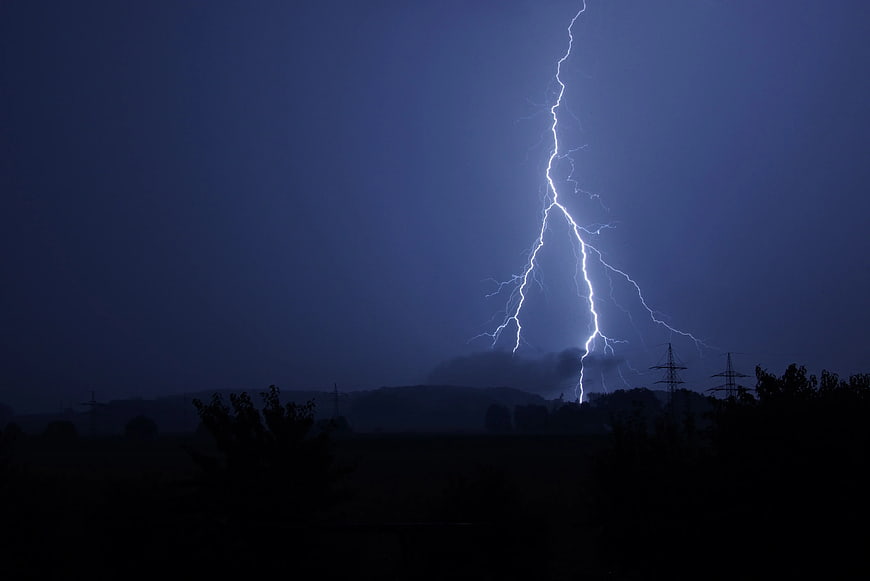 Dramatic Lightning Strike Over Dark Rural Landscape at Night