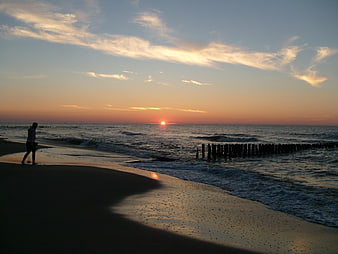 Silhouette of Person Walking on Beach at Sunset