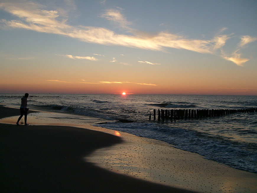 Silhouette of Person Walking on Beach at Sunset