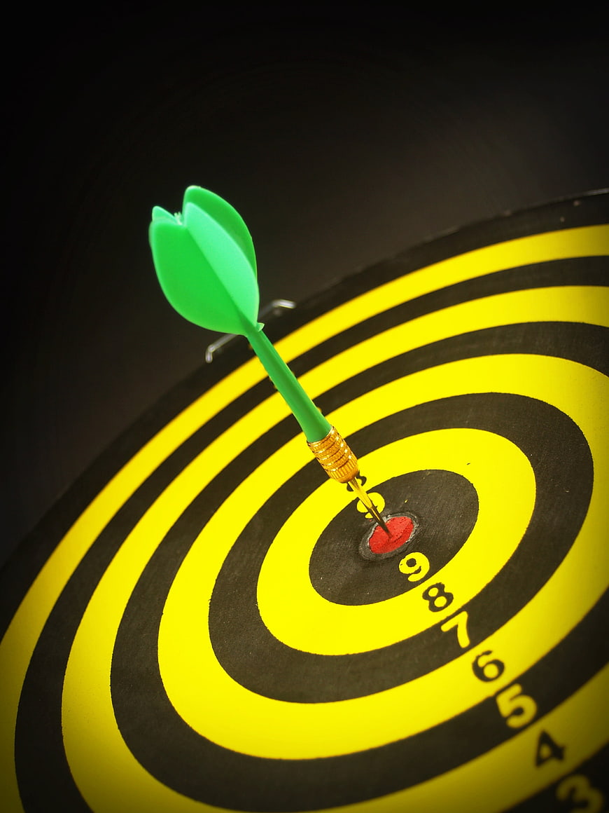 Green Dart Hitting Bullseye On Black And Yellow Target
