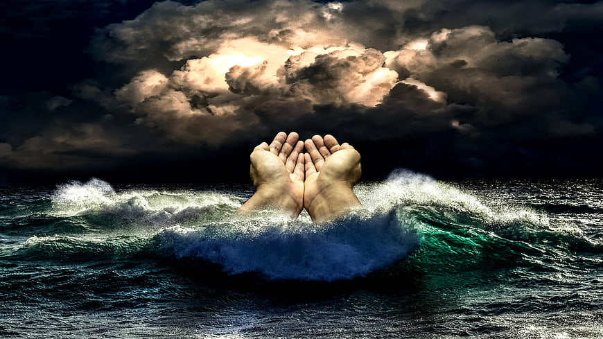 Hands cupping feet emerging from stormy ocean waves