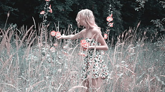 Young woman in floral dress touching flowers in a field