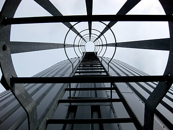 Low angle view of metal ladder ascending industrial tower structure