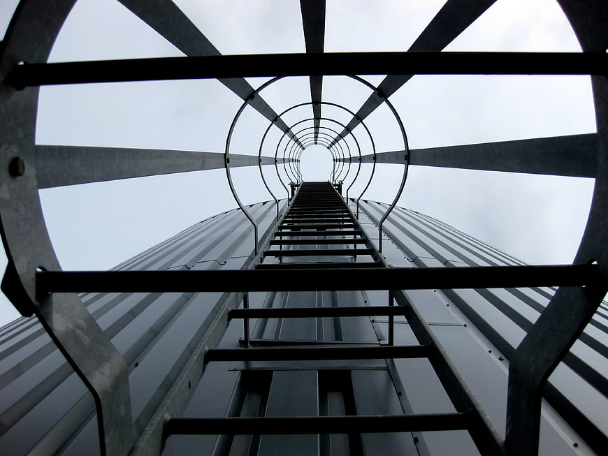 Low angle view of metal ladder ascending industrial tower structure