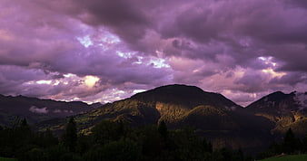 Dramatic Purple Clouds Over Mountain Landscape at Sunset