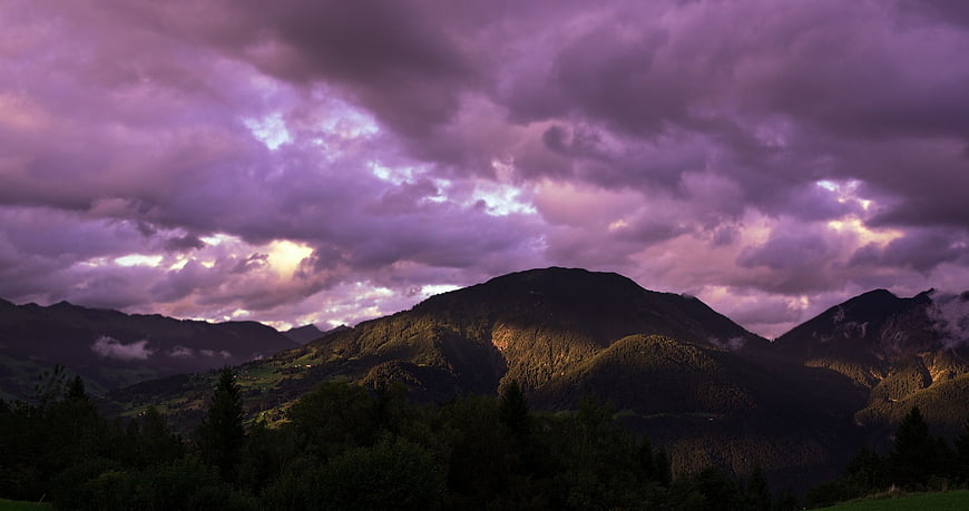 Dramatic Purple Clouds Over Mountain Landscape at Sunset