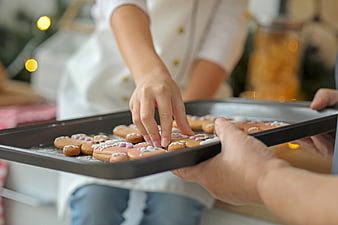 Child decorating gingerbread cookies on baking sheet