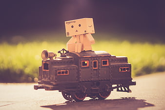 Cardboard robot figure riding a vintage toy train outdoors