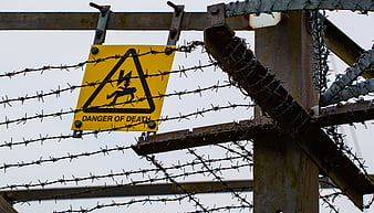 Danger of death warning sign behind barbed wire fence