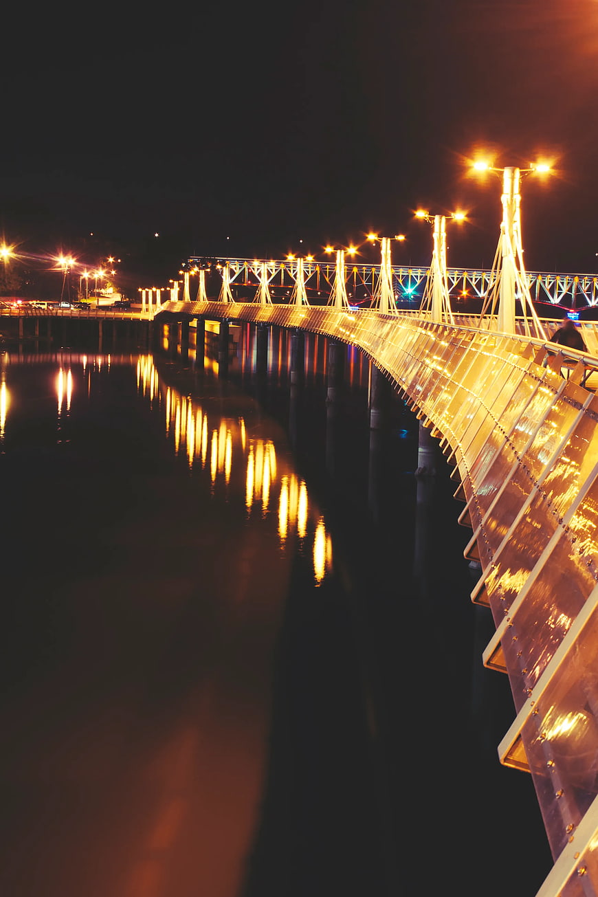 Illuminated modern bridge at night with water reflections