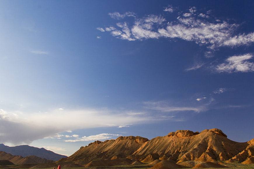 Golden Danxia landforms under vast blue sky with clouds