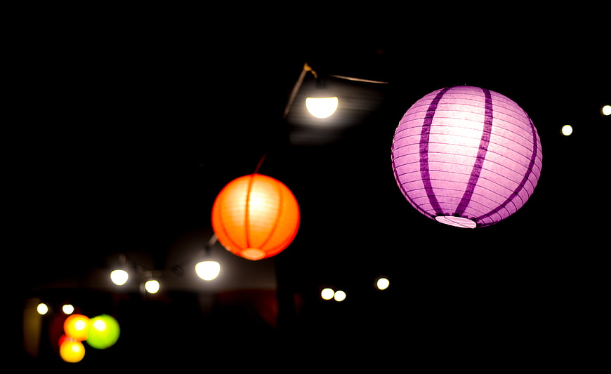 Glowing purple and orange paper lanterns at night