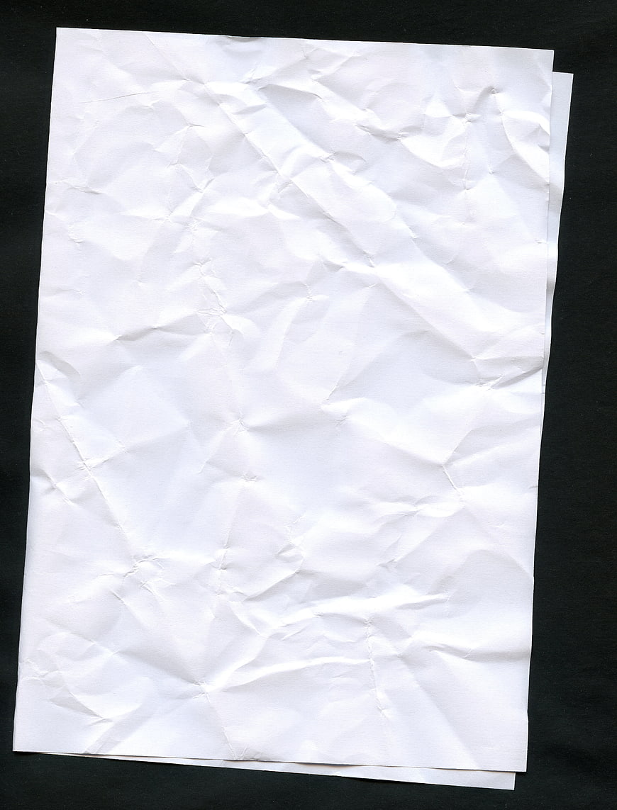 Crumpled white paper texture on black background