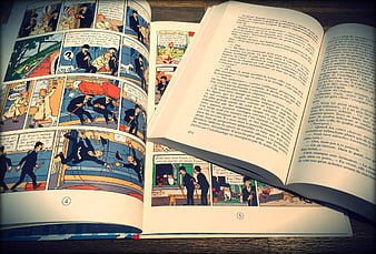 Open vintage comic book and novel on wooden table