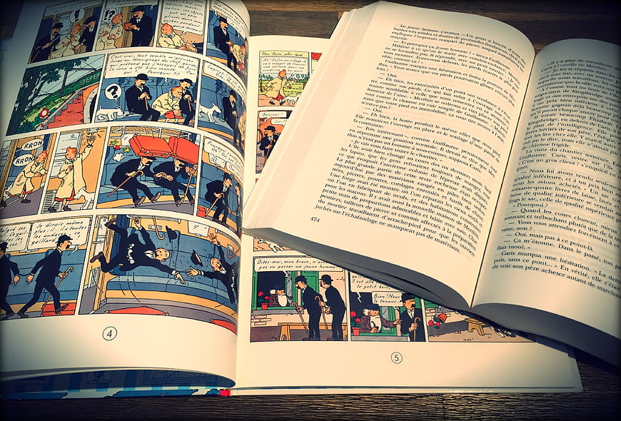 Open vintage comic book and novel on wooden table