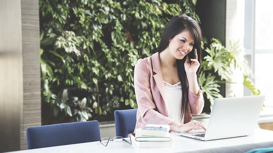 Smiling businesswoman talking on phone at office desk