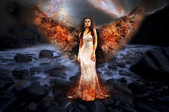Woman in white dress with fiery wings standing in rocky river