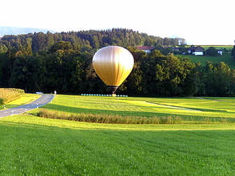 Golden Hot Air Balloon Landing in Green Pastoral Field
