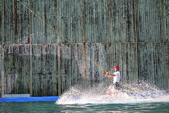 Man Wakeboarding on Cable System with Industrial Background