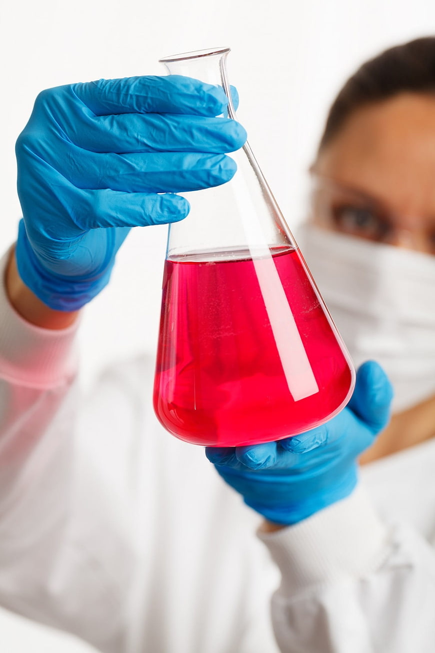Scientist holding flask with red liquid in laboratory