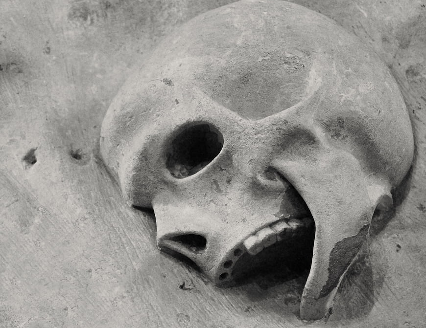 Close-up of weathered stone skull sculpture in church