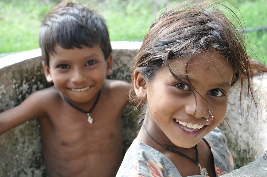 Two smiling children in a concrete well outdoors