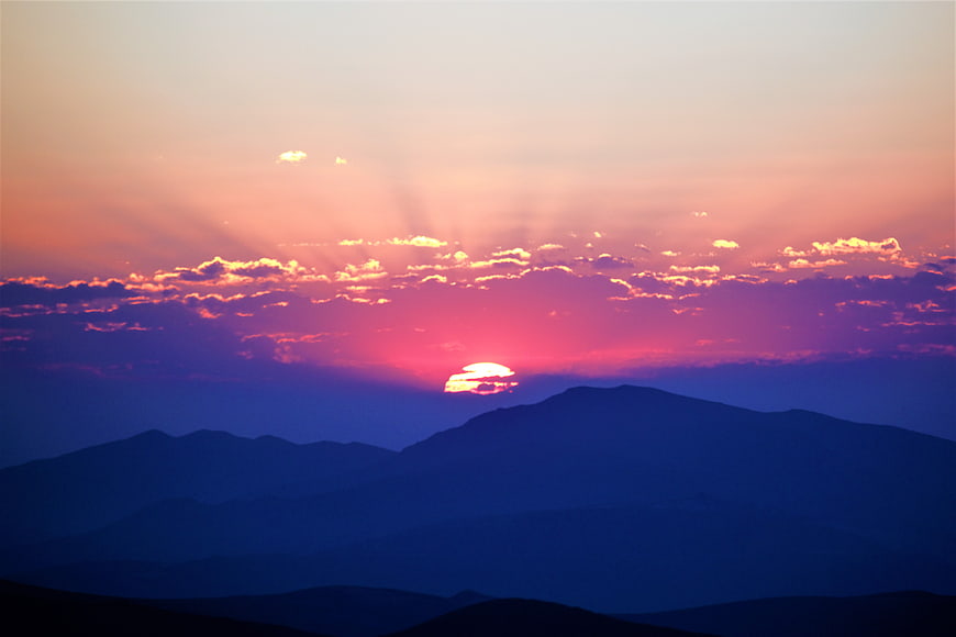 Vibrant Sunrise Over Layered Mountain Silhouettes