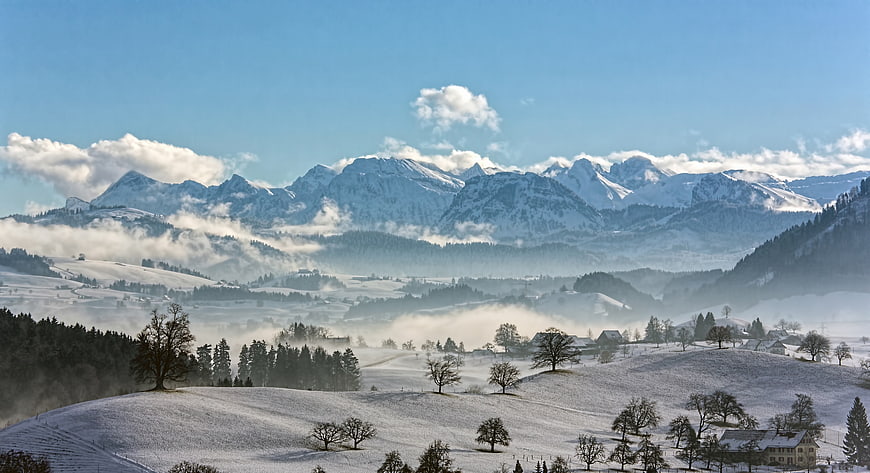 Snowy Mountain Landscape with Misty Valley and Winter Village