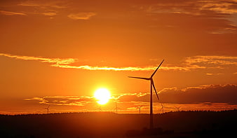Wind Turbines Silhouette Against Vibrant Orange Sunset Sky