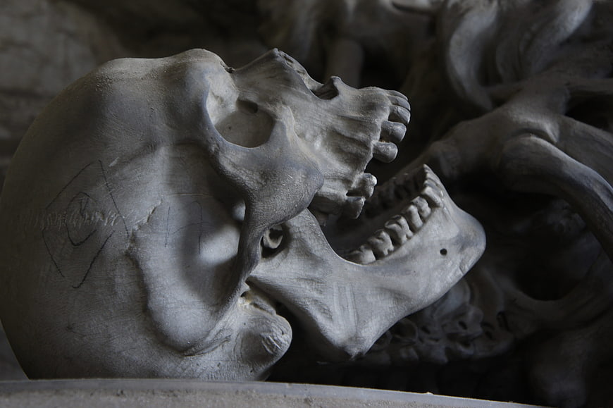 Close-up of weathered human skulls in a dimly lit ossuary