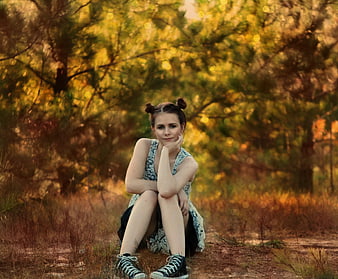 Young woman sitting in forest with double buns hairstyle