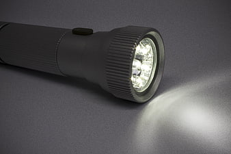 Illuminated LED Flashlight Close-Up On Gray Background